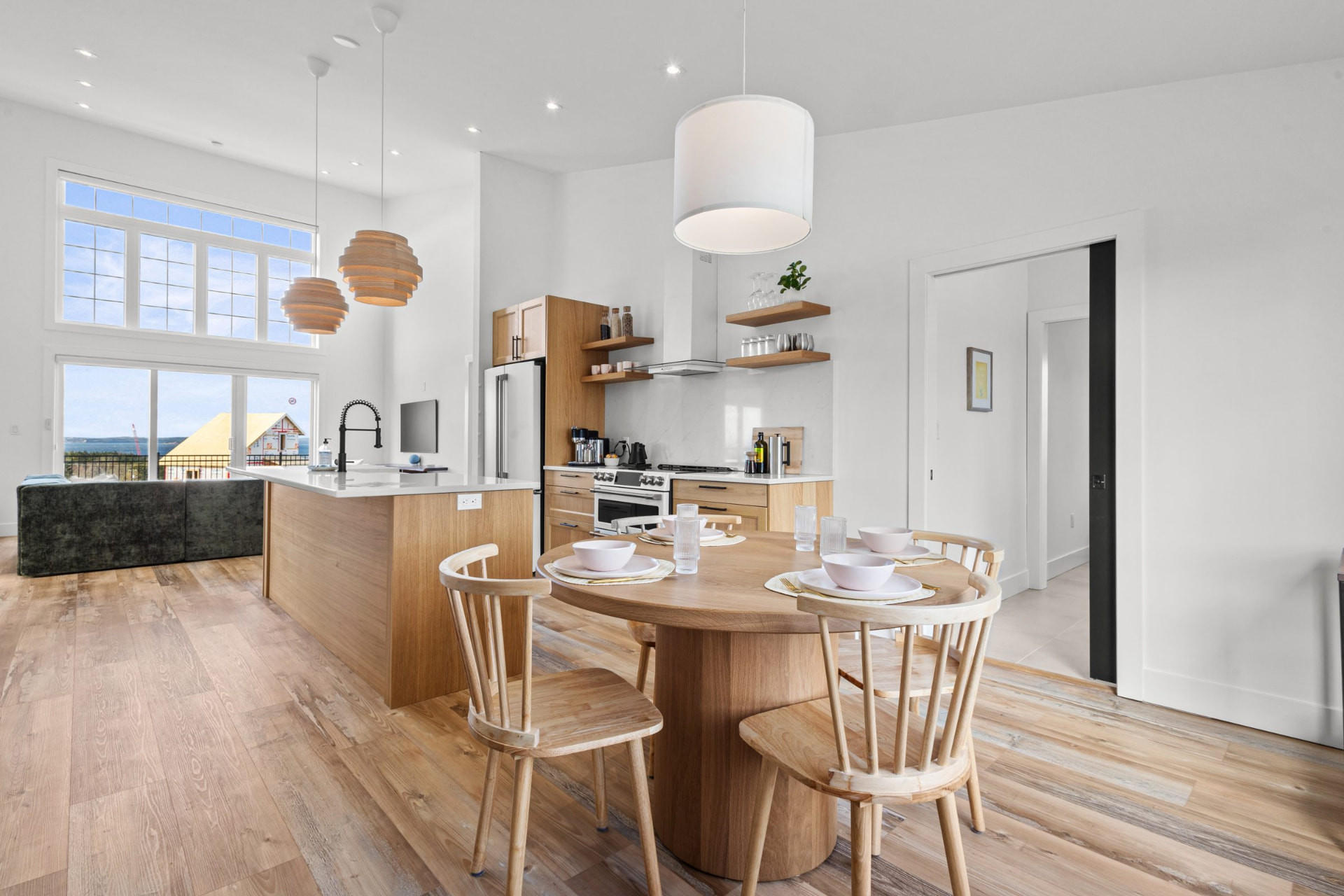 Full kitchen with island and dining table beside the living space